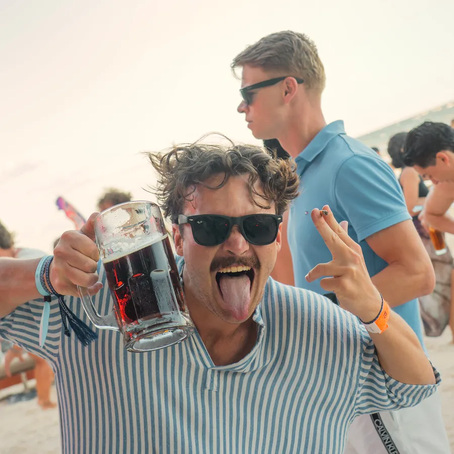 A guest raising his drink on the sand